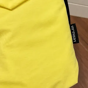 Dettaglio del tessuto in nylon giallo brillante con etichetta nera e trama increspata