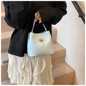 Detail of light blue lychee pattern leather bucket bag with gold twist lock and top handle