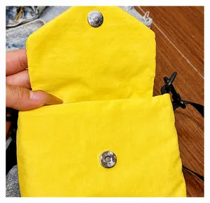Dettaglio della chiusura magnetica e del tessuto in nylon della mini borsa gialla