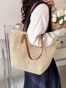 Sac fourre-tout beige en paille tissée avec anses en cuir marron porté par un mannequin