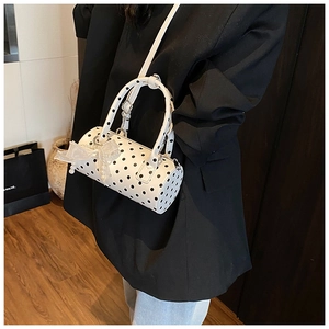 Cylindrical polka dot shoulder bag with mesh bow detail shown on a stylish model