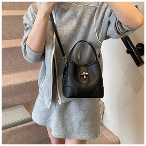 Detail of black lychee grain bucket bag featuring a gold clasp and model hand-carrying style