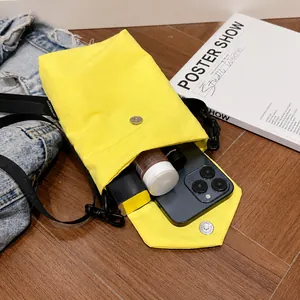 Dettaglio dell'interno della borsa per telefono in nylon giallo con smartphone e trucchi
