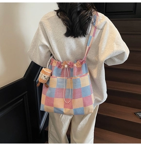 Detailed close-up of a colorful striped tote bag with drawstring closure and plush pendant