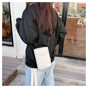 Vista esterna di una mini borsa a tracolla in nylon beige con trama sottile effetto carta
