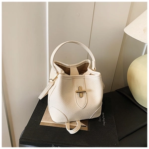 Close-up of beige lychee grain leather bucket bag with golden metal twist lock detail