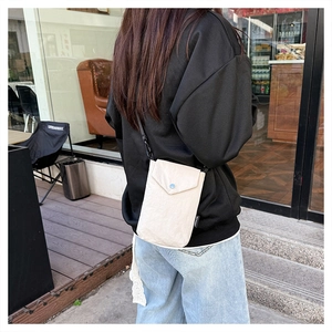 Vista dettagliata di una mini borsa a tracolla in nylon crema minimalista su una modella