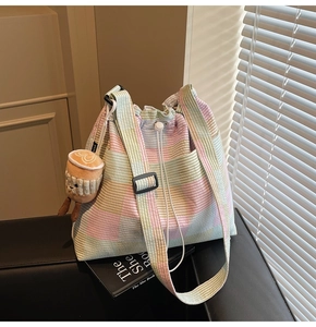 Close-up of corduroy checkered bucket bag with drawstring closure and plush cup charm