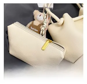 Detailed view of beige pebble grain bucket bag with gold hardware and fashion bear charm