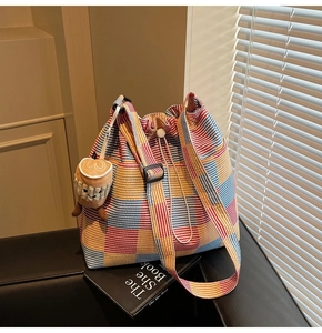Detailed view of colorful striped bucket bag featuring drawstring and coffee cup plush charm