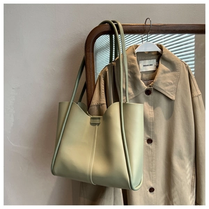 Detail of mint green tote bag with unique wavy edge and slender shoulder straps