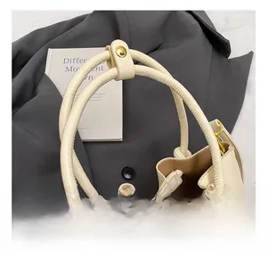 Close-up of cream pleated bucket bag with litchi grain leather and golden hardware