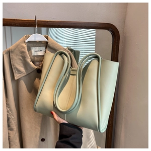 Close-up of a large light green tote bag with durable faux leather and shoulder straps