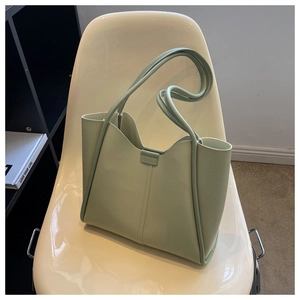 Detail of mint green tote bag with wave-edge design on a modern white chair