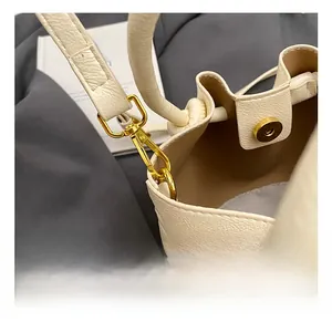 Close-up of golden alloy hooks and magnetic closure on cream lychee grain leather handbag