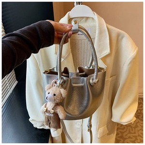 Detail of silver metallic bucket bag with drawstring and cute teddy bear pendant