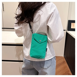 Dettaglio della mini borsa a tracolla in nylon verde acceso per cellulare con jeans