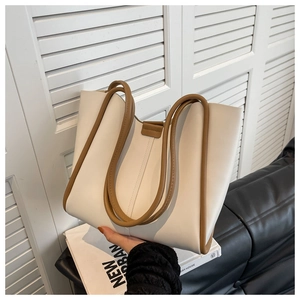 Detail of a minimalist cream tote bag with caramel trim and durable double handles