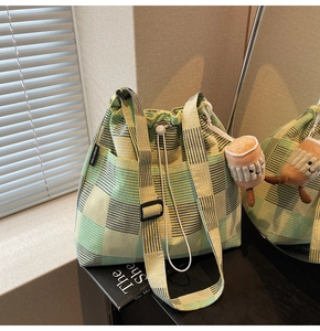 Detail of plaid canvas bucket bag with drawstring closure and plush marshmallow charm