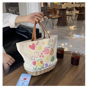 Dettaglio della borsa tote in tela con stampa cartoon e fondo in paglia intrecciata