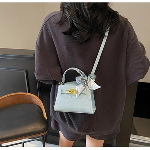 Détail du sac à main bleu clair à motif croco avec foulard en soie sur l'épaule