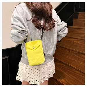 Dettaglio di una mini borsa a tracolla in nylon giallo acceso con bottone e cordino nero