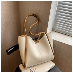Detail of minimalist cream tote bag with brown piping and leather strap on books