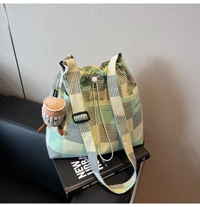 Detail of checkered canvas bucket bag with drawstring closure and cute plush charm