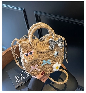 Détail du sac en paille fait main avec breloque ours et éléments floraux décoratifs
