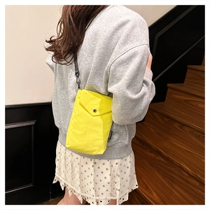 Dettaglio della borsa porta cellulare gialla in nylon con bottone in metallo ed etichetta