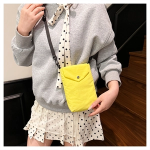 Mini borsa a tracolla in nylon giallo limone con tracolla regolabile su felpa grigia