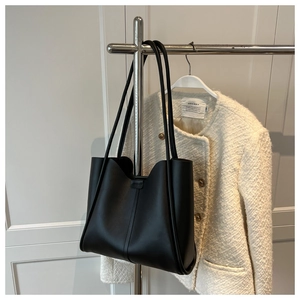 Detail of minimalist black leather tote bag with elegant thin straps and vertical stitching