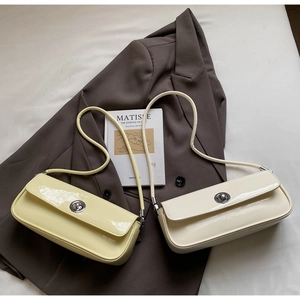 Flachbild von glänzenden Baguette-Taschen aus Lackleder in Beige und Gelb mit Silberschnallen