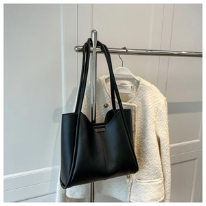 Detail view of black minimalist tote bag with reinforced handles on metal hanger
