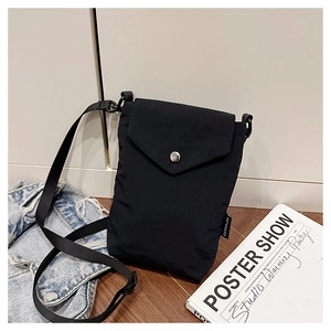 Dettaglio della mini borsa in nylon nero su pavimento in legno con tracolla