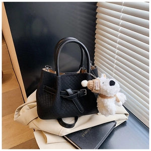 Détail du sac à main noir tressé avec boucle et breloque peluche chiot blanc mignon