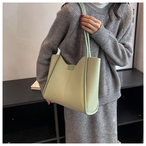 Close-up of light green minimalist tote bag with vertical stitching and thin shoulder strap