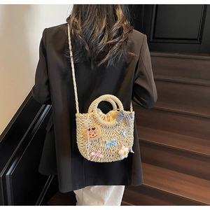 Détail d'un sac en paille tressée avec breloque ours et rubans décoratifs
