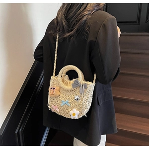 Sac seau en paille avec oursons porté par un mannequin vêtu d'un blazer noir élégant