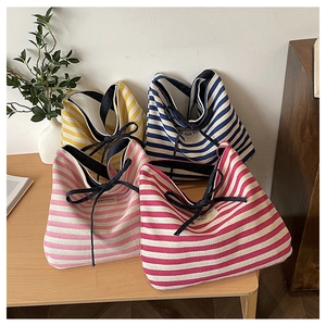 Detail view of striped canvas tote bags in four colors with braided rope handles and labels
