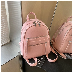 Detail of pink faux leather backpack with pebble texture and silver metal zippers