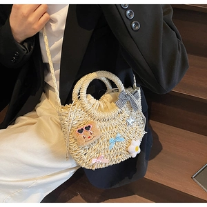 Détail du sac de plage en paille tressée avec ours en peluche et breloques