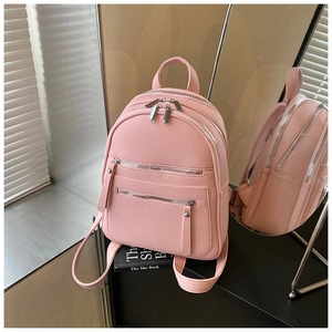Detail view of pink leather backpack with multiple zipper pockets in a mirror reflection
