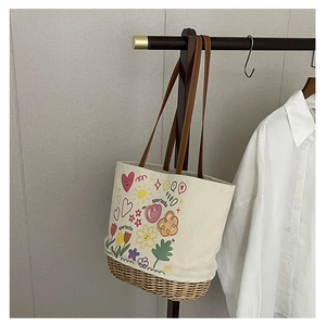 Dettaglio di borsa tote in tela stampata con base in paglia e manici in pelle marrone