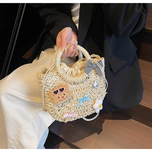 Détails d'un sac en paille tissé beige avec breloques d'ours mignon et cordon de serrage