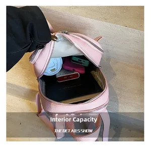 Detail view of pink PU leather backpack interior storage with books and accessories