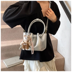 Detail of silver pleated bucket bag with metallic texture and cute bear charm pendant
