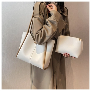 Detail of elegant cream tote bag and matching pouch with brown leather straps and piping