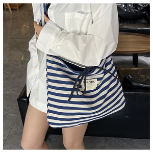 Detail of blue and white striped canvas tote bag with drawstring closure and text label