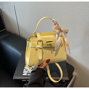 Détail du sac en cuir jaune texture crocodile avec foulard en soie et boucle métal